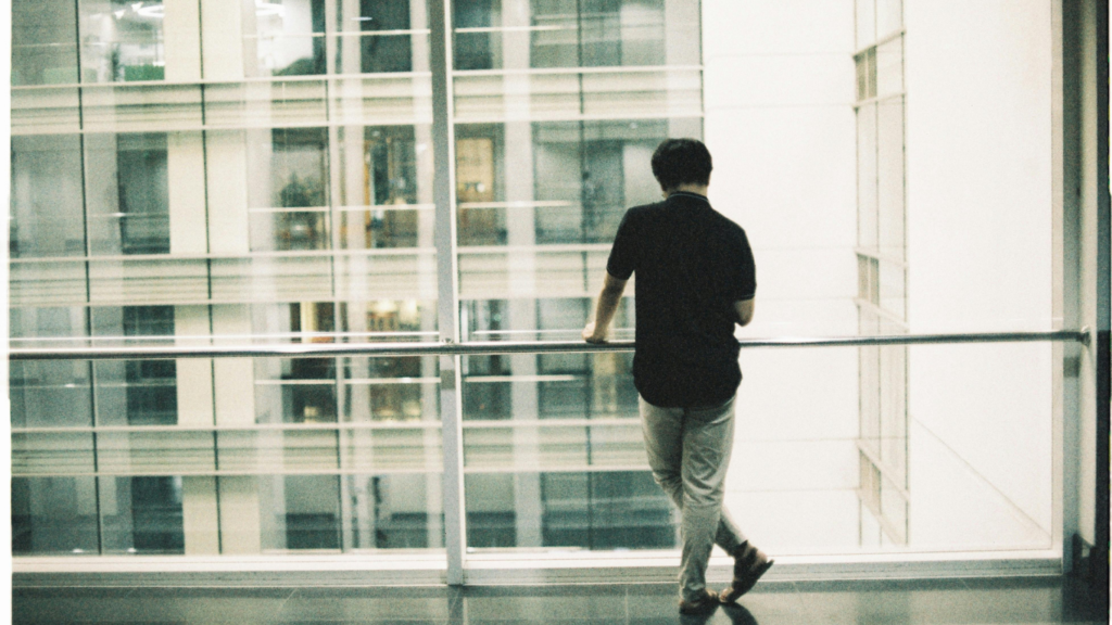 Homem de costa em uma sacada refletindo