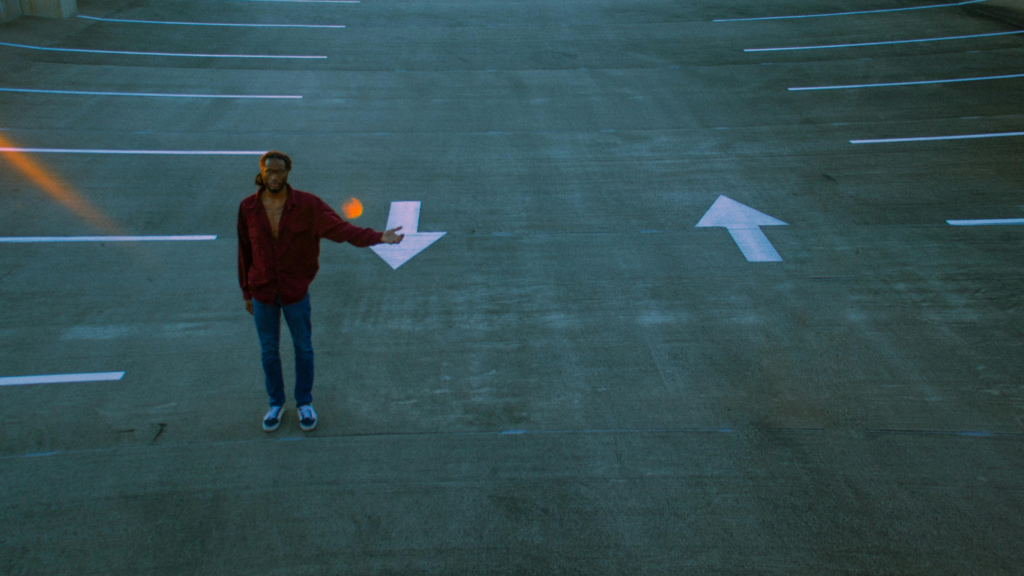 Homem em um estacionamento apontando para as flechas