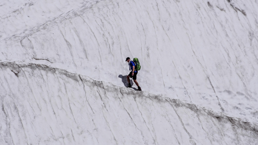 Homem caminhando em uma montanha na neve