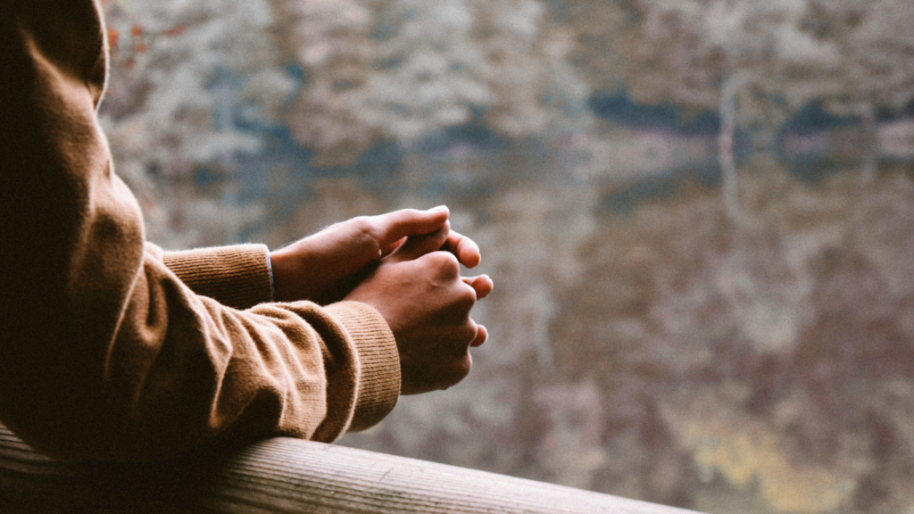 Homem encostado com os braços apoiados refletindo
