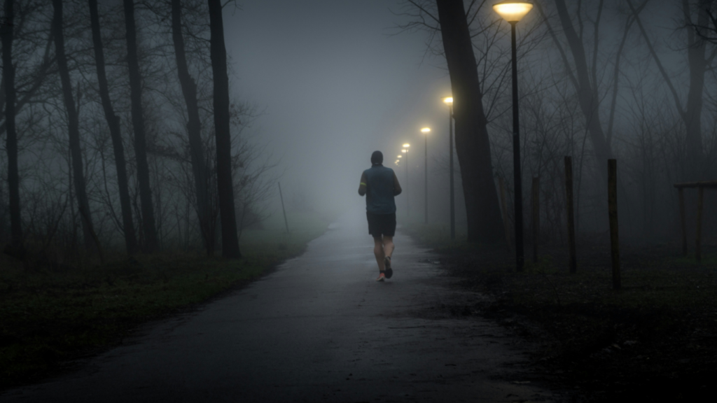 Homem correndo a noite em uma estrada escura