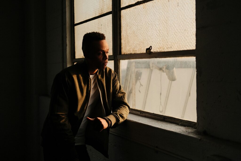 homem refletindo sozinho na janela simbolizando conflito mental