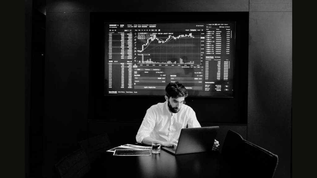 Homem sentado analisando o grafico financeiro no computador